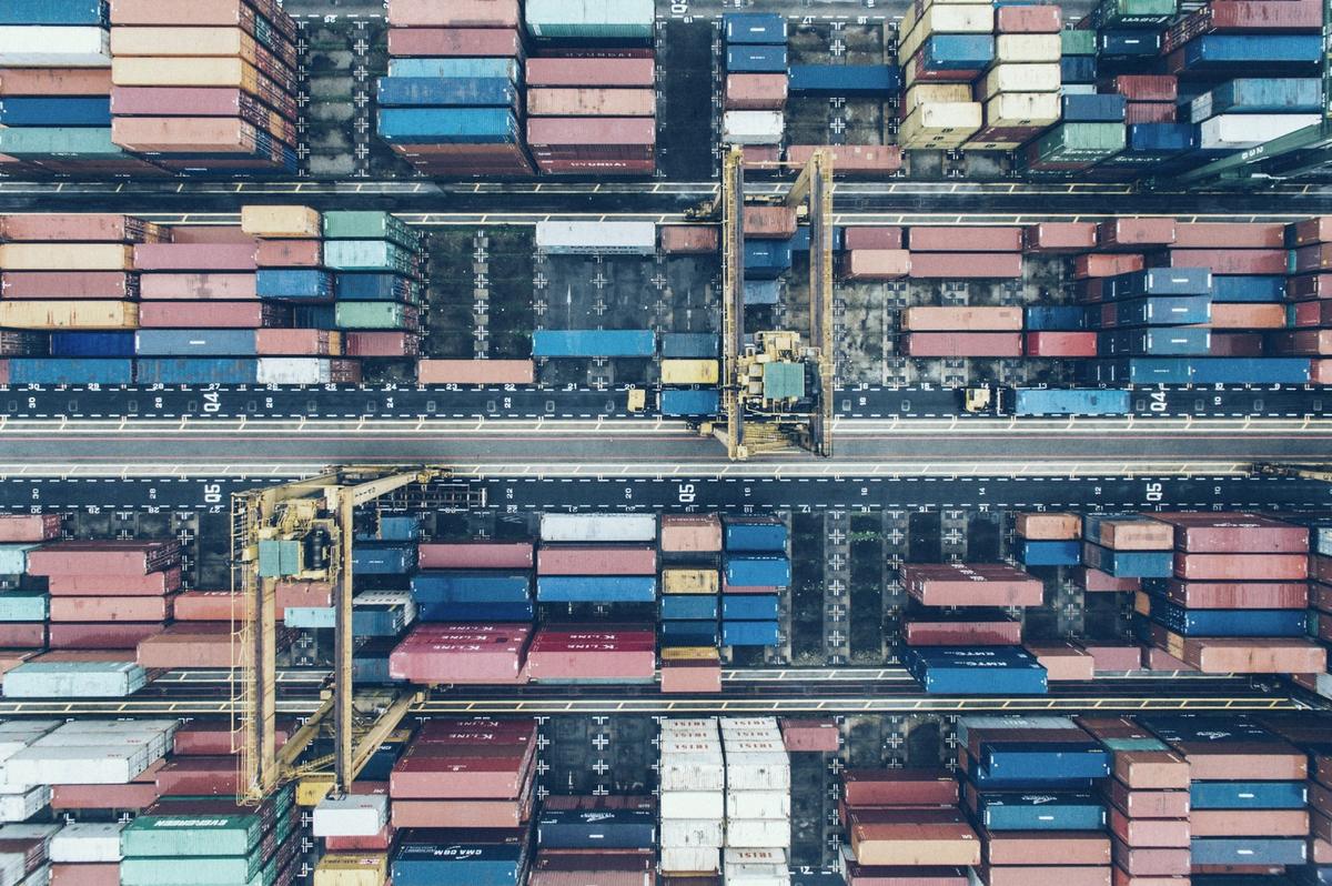 Een containerterminal in een haven, vanuit de lucht: containers in lange rijen en portaalkranen.