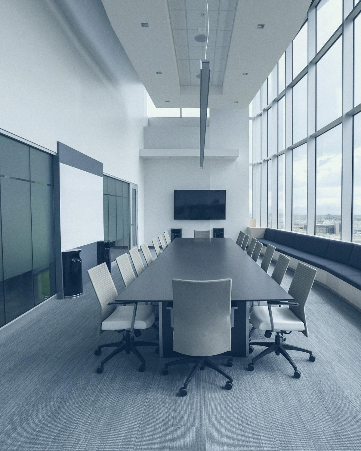 Une salle de réunion vide, une longue table face à une baie vitrée.